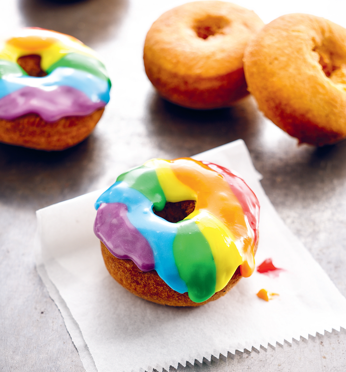 Four Cake Doughnuts on a counter, two with Rainbow Glaze frosting.